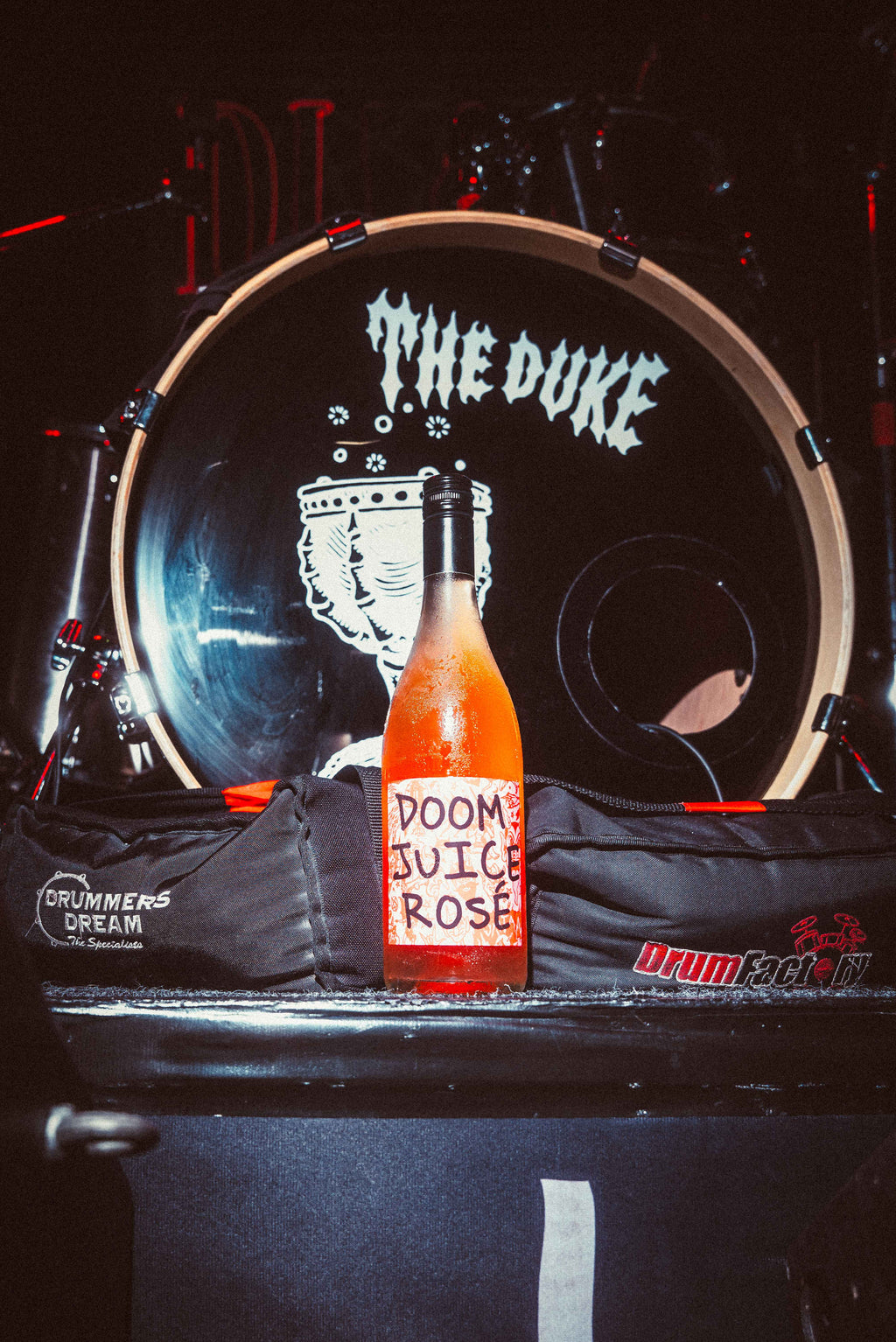 Bottle of 'Dooms Juice Rose' on a drum set with 'The Duke' branding.