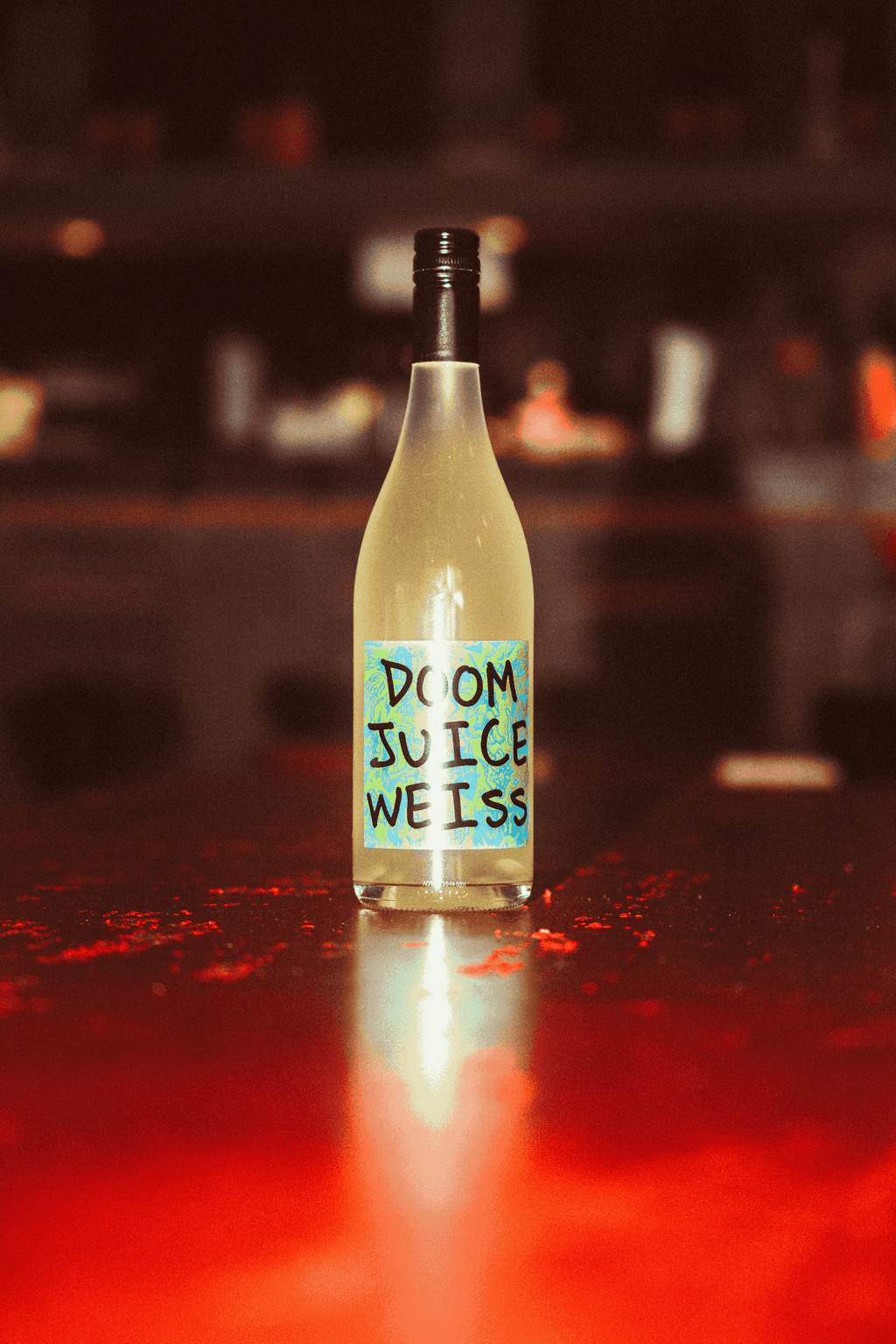 Bottle of Doom Juice Weiss on a red surface with blurred background