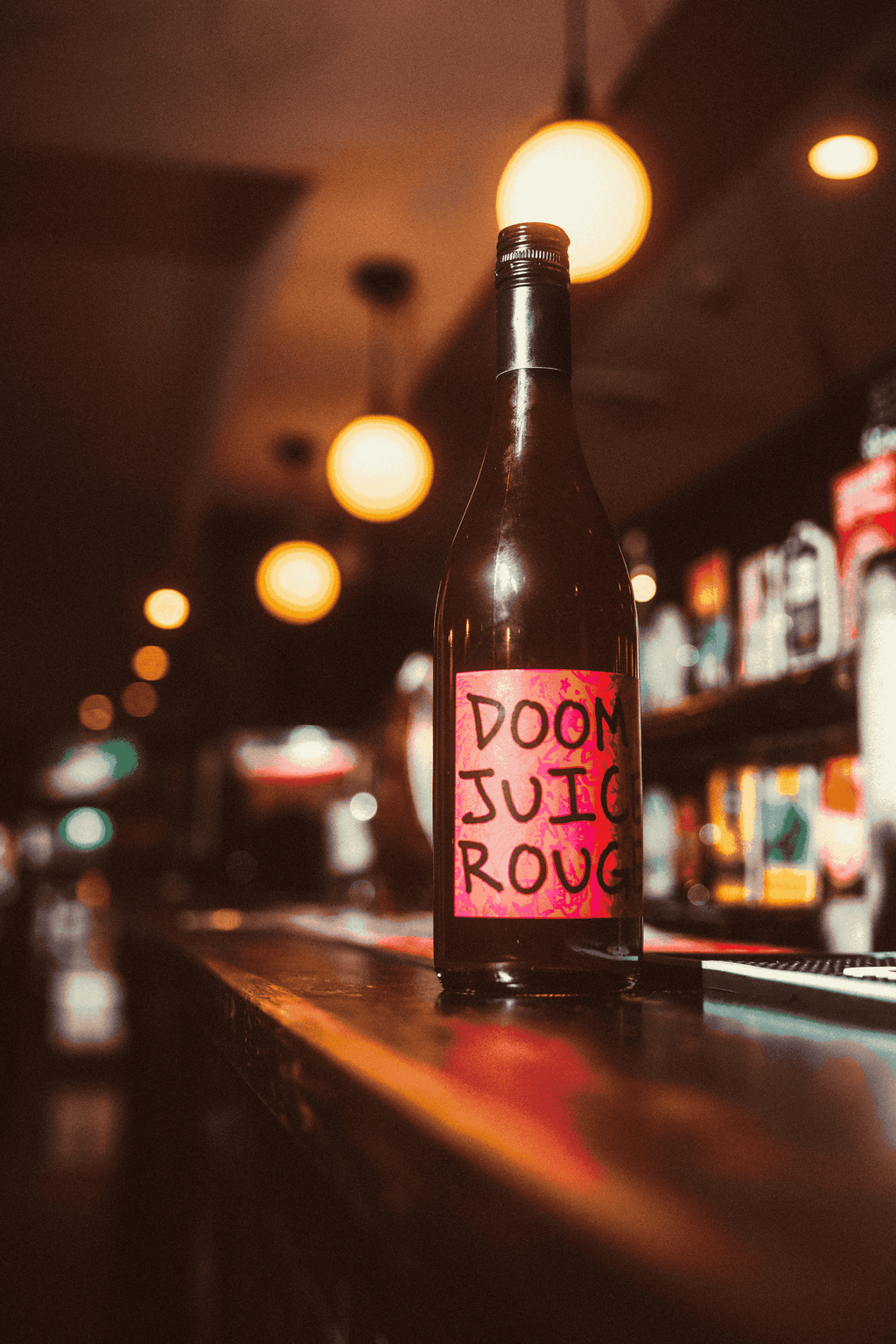 Bottle of Doom Juice Rouge on a bar counter with a blurred bar background