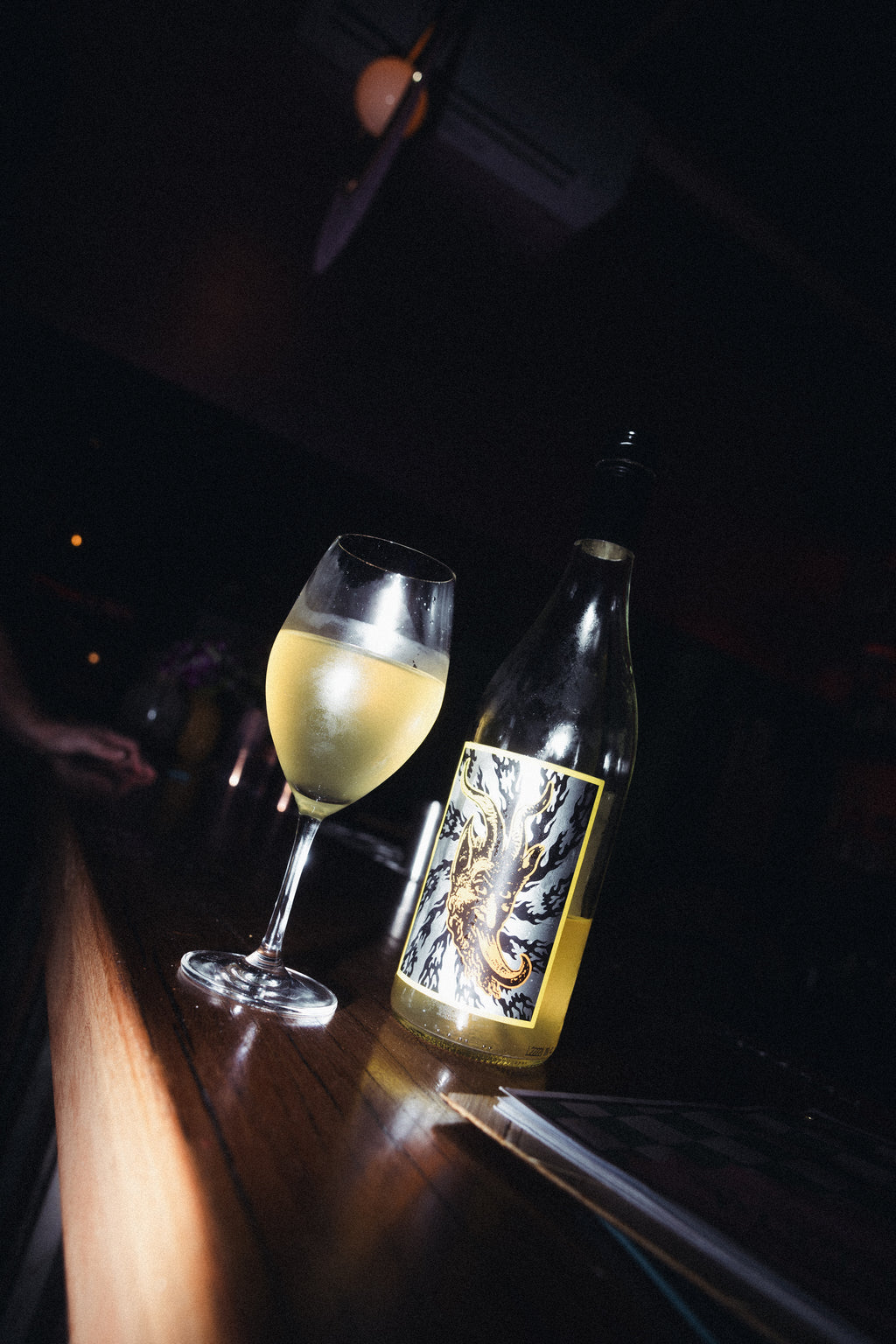 Bottle and glass of Doom Juice wine on a dark surface
