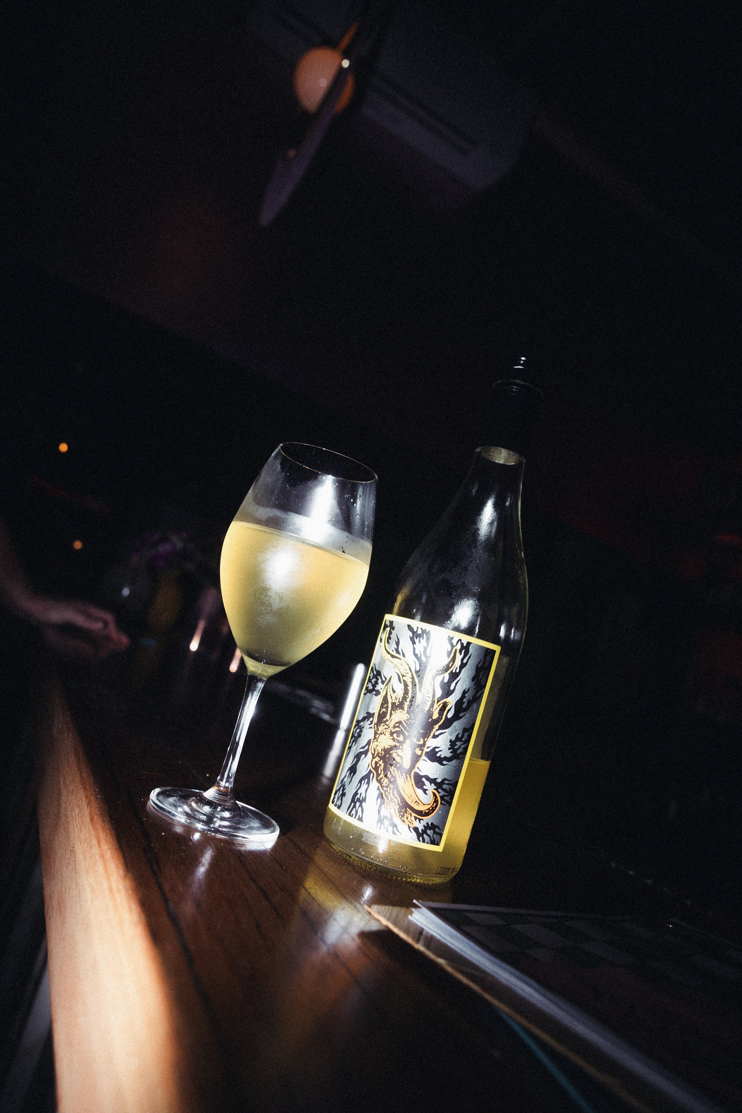 Bottle and glass of Doom Juice wine on a dark surface