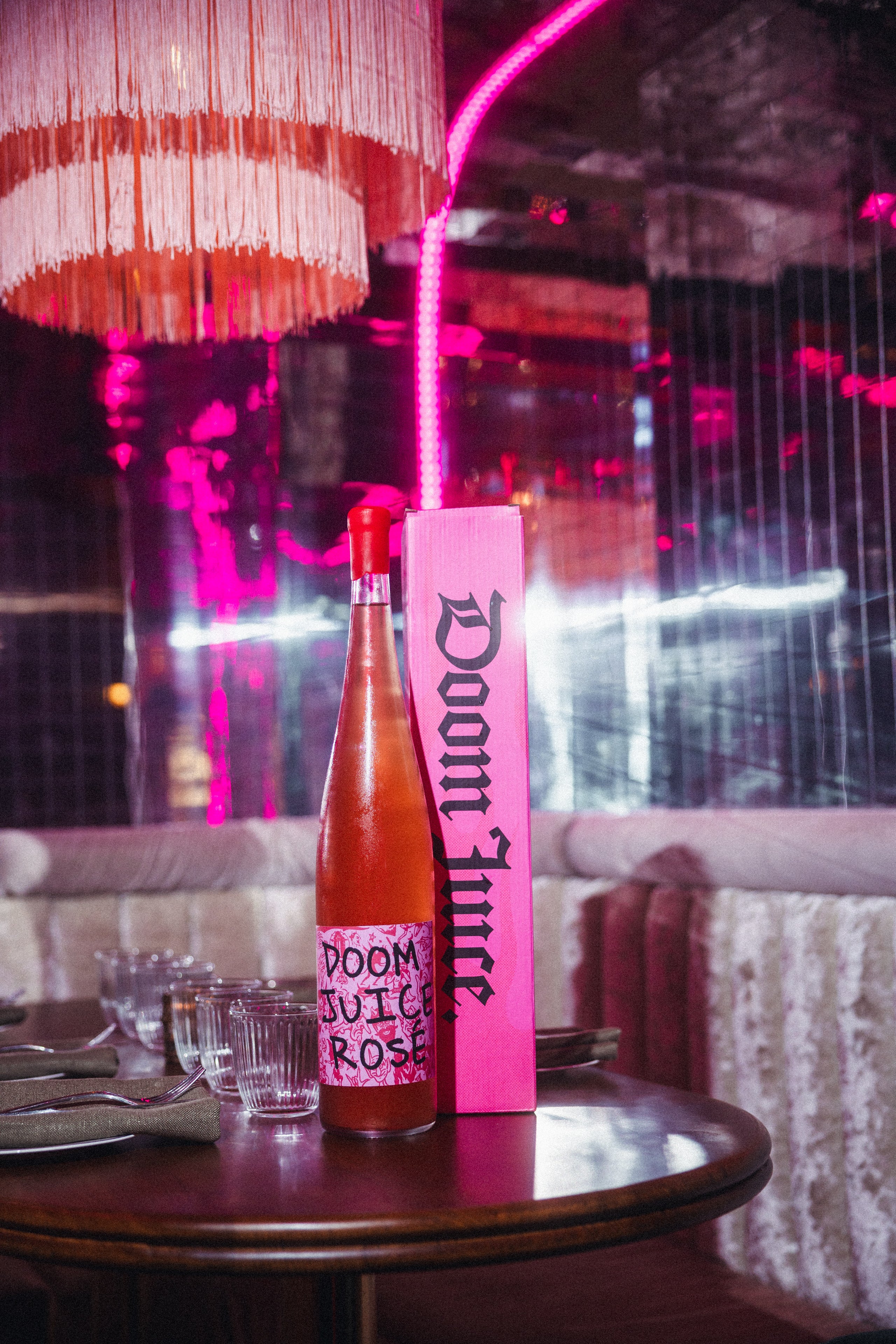Bottle of Doom Juice Rosé and packaging on a table with a cityscape background