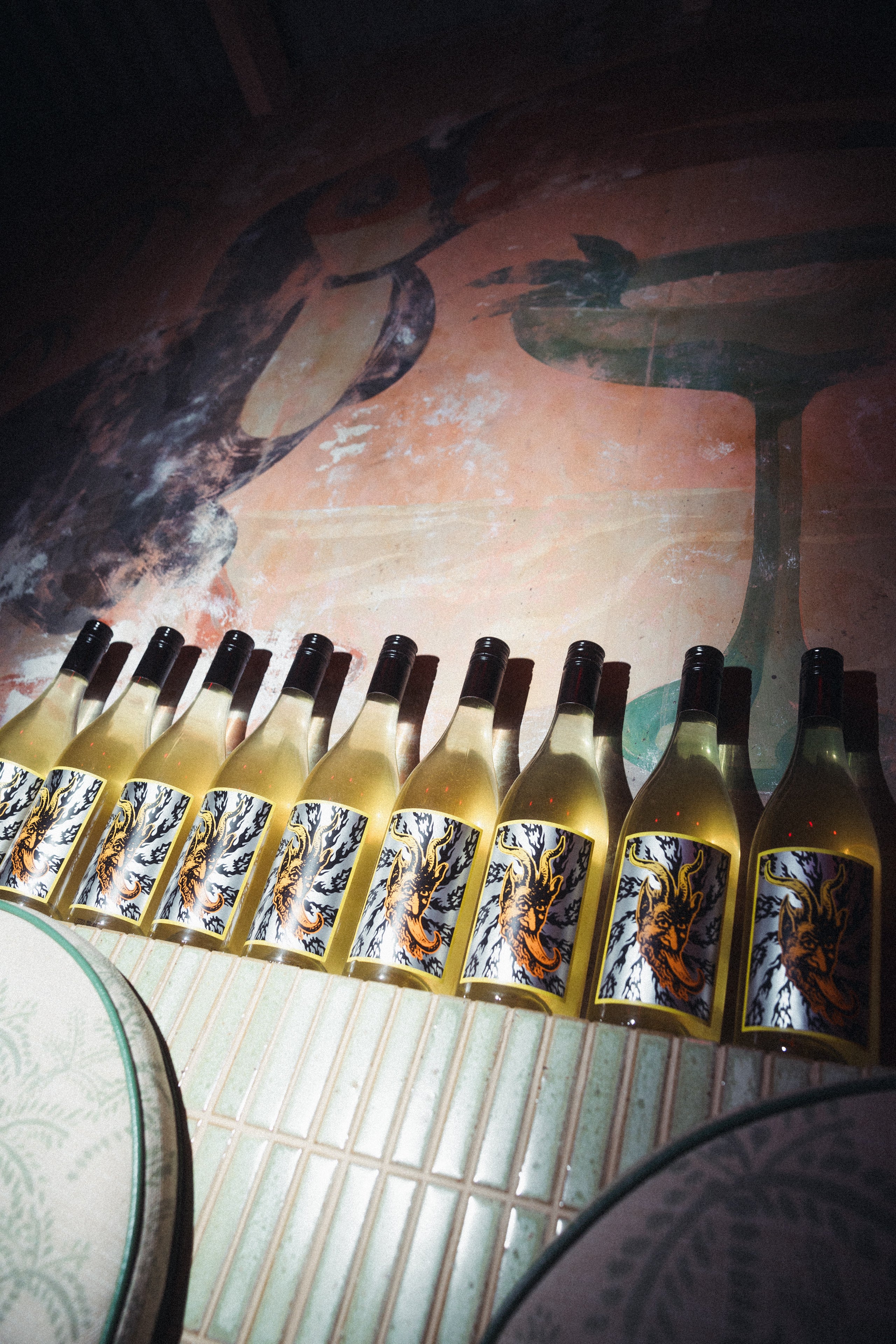 Row of wine bottles with decorative labels on a rustic surface.