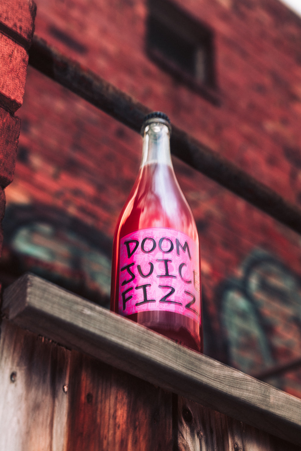 Bottle of 'Doom Juice Fizz' against a brick wall
