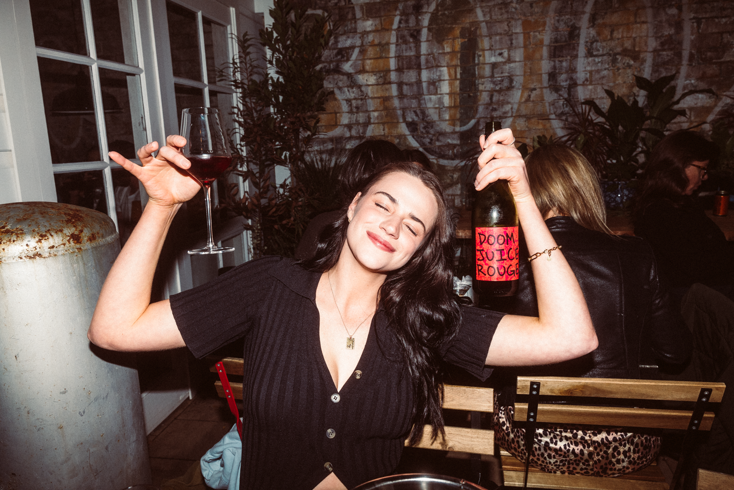 Woman holding a bottle and glass in an indoor setting with a casual atmosphere