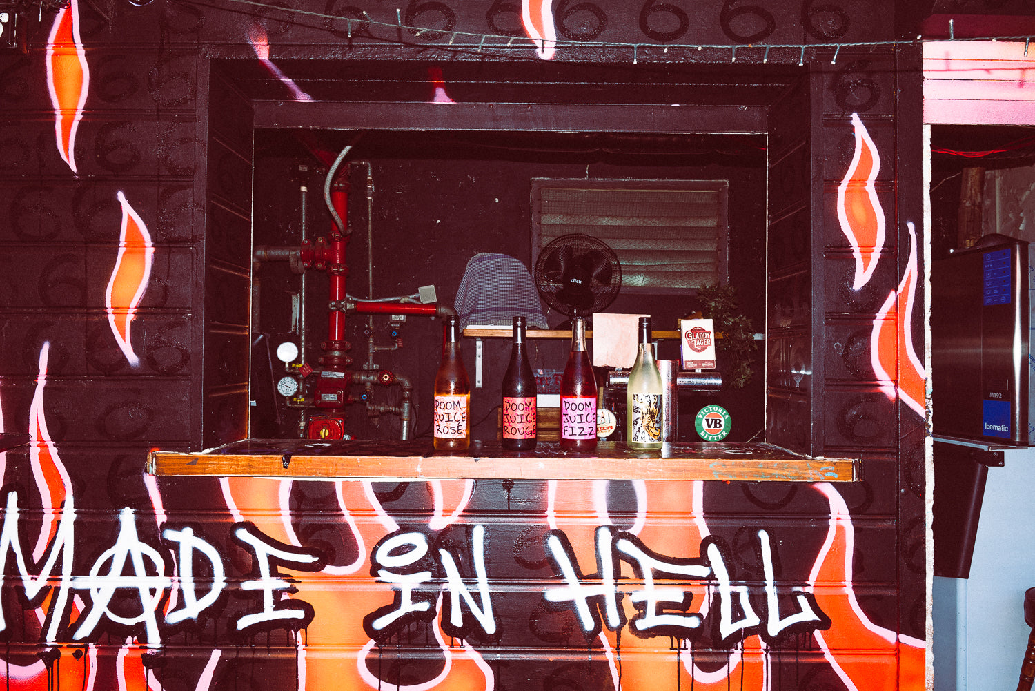 Bar area with bottles and a 'Made in Hell' sign on a fiery background