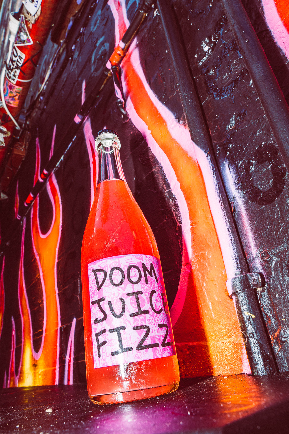 Bottle labeled 'Doom Juic Fizz' against a colorful, abstract background