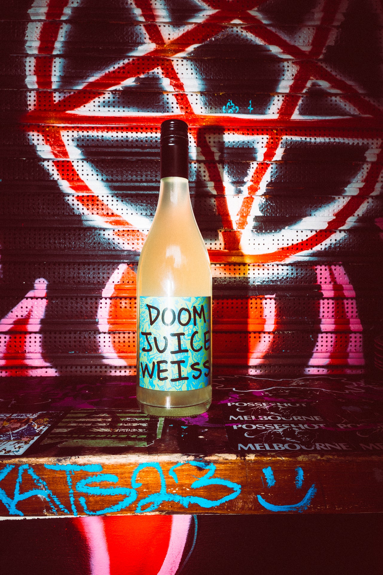 Bottle of Doom Juice Weiss on a reflective surface with colorful geometric patterns in the background
